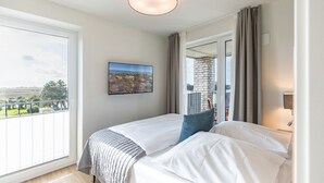 Et soveværelse med et stort vindue, en seng, et billede og udsigt til en balkon.