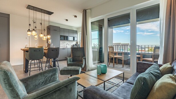 Ein modernes Wohnzimmer mit einer Couch, Sesseln und einem Essbereich mit Tisch und Stühlen.