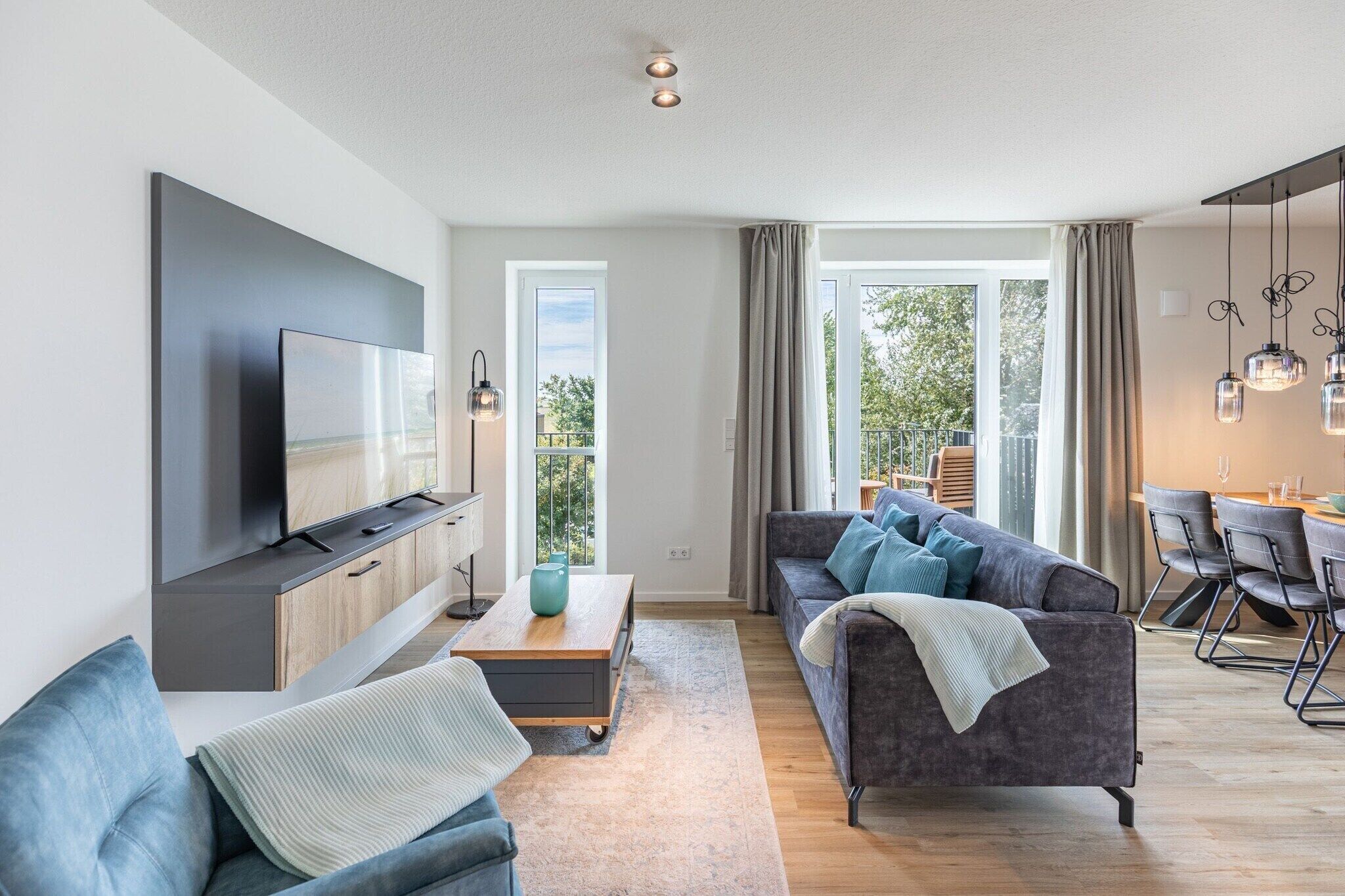 Uma sala de estar moderna com televisão de tela plana, sofá e área de jantar.