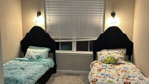 A bedroom with two single beds, a ceiling fan, and a window with blinds. - Charming 2BR/2BA Bed — Cozy, Quiet & Welcoming (McDonough)