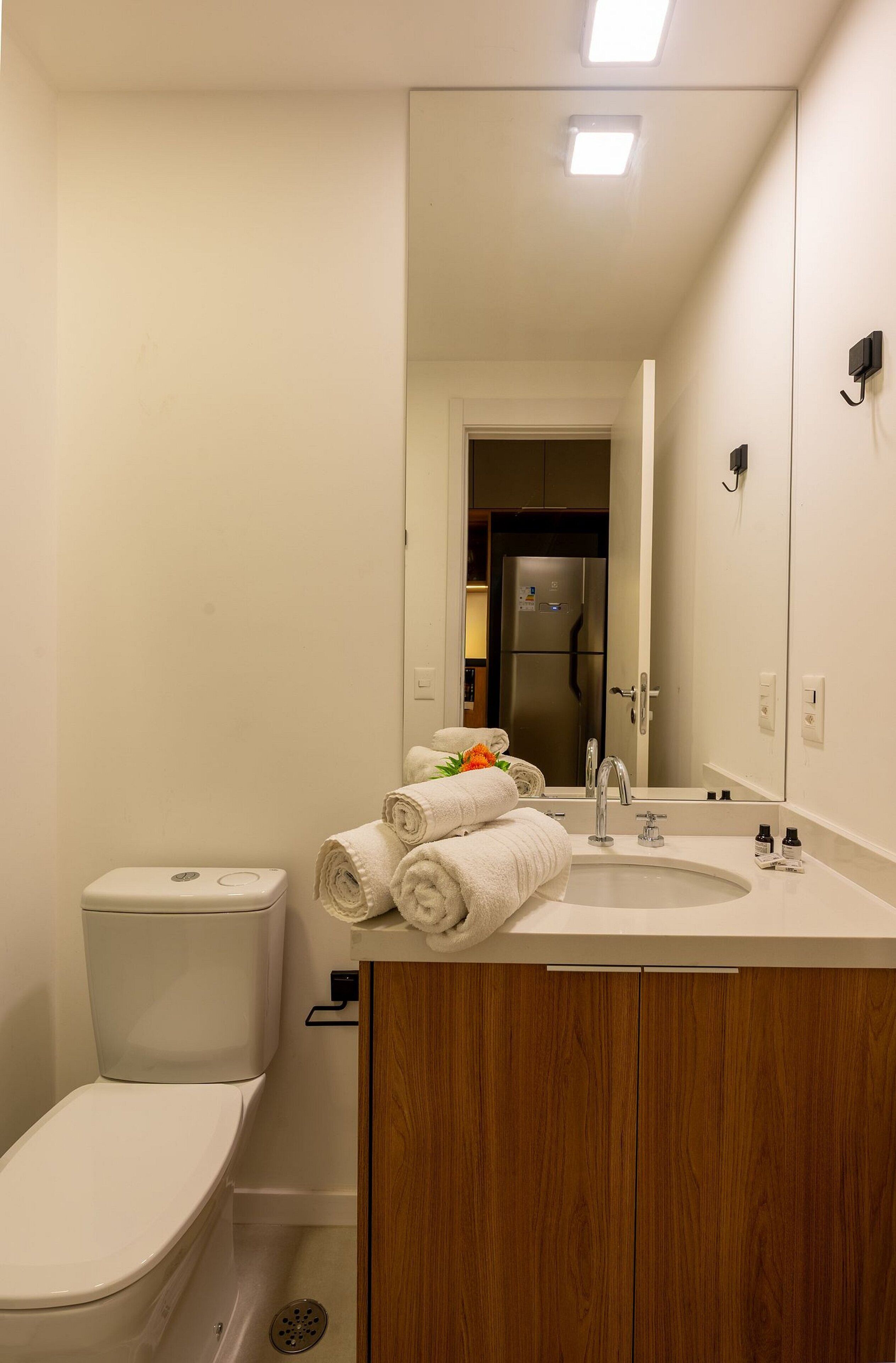 Un baño moderno con inodoro, lavamanos y espejo.