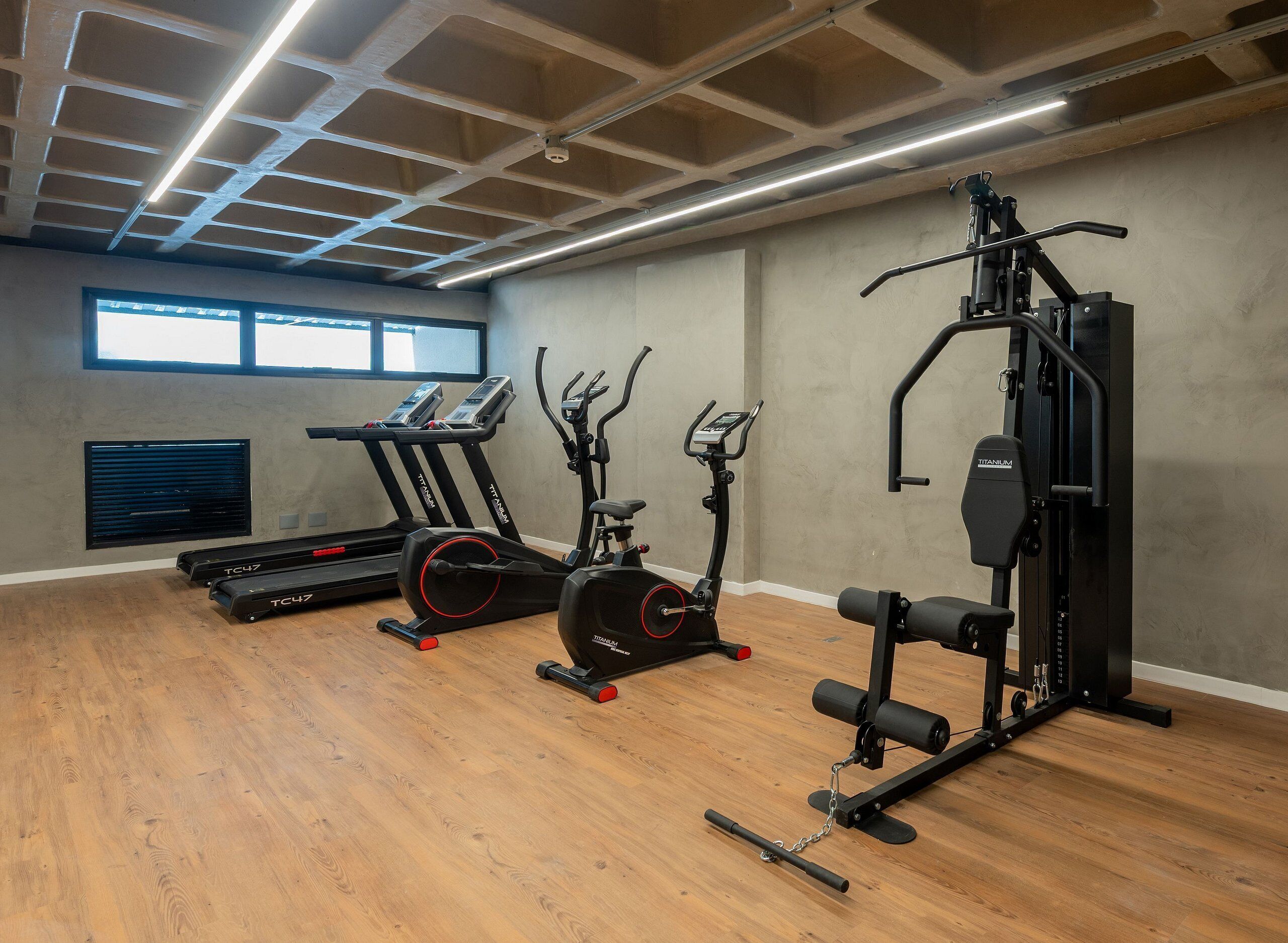 Un gimnasio con cintas de correr, elípticas y una jaula de sentadillas.