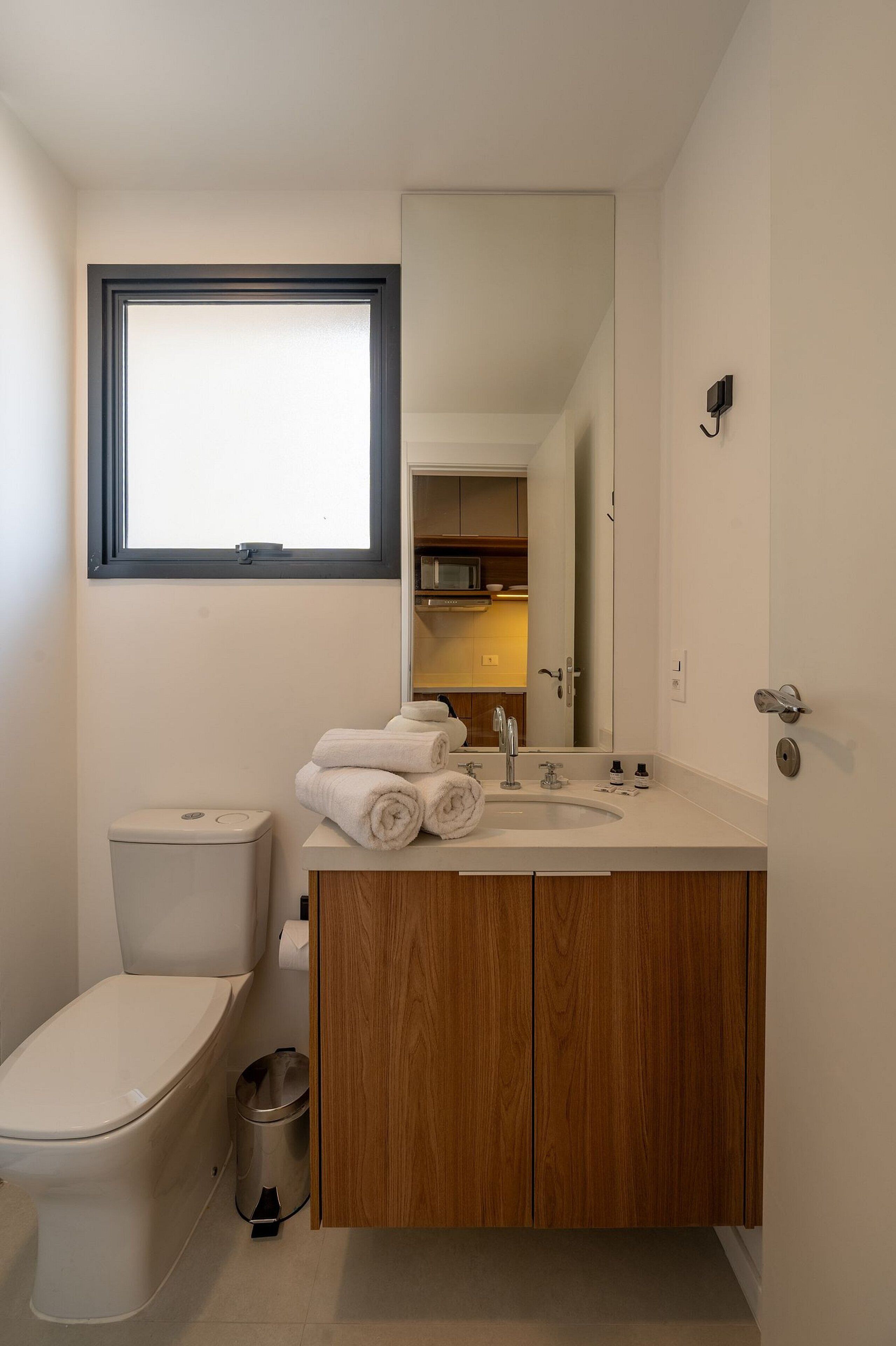 A modern bathroom with a toilet, sink, and mirror.