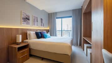 A modern hotel room with a large bed, a nightstand, and a wardrobe.
