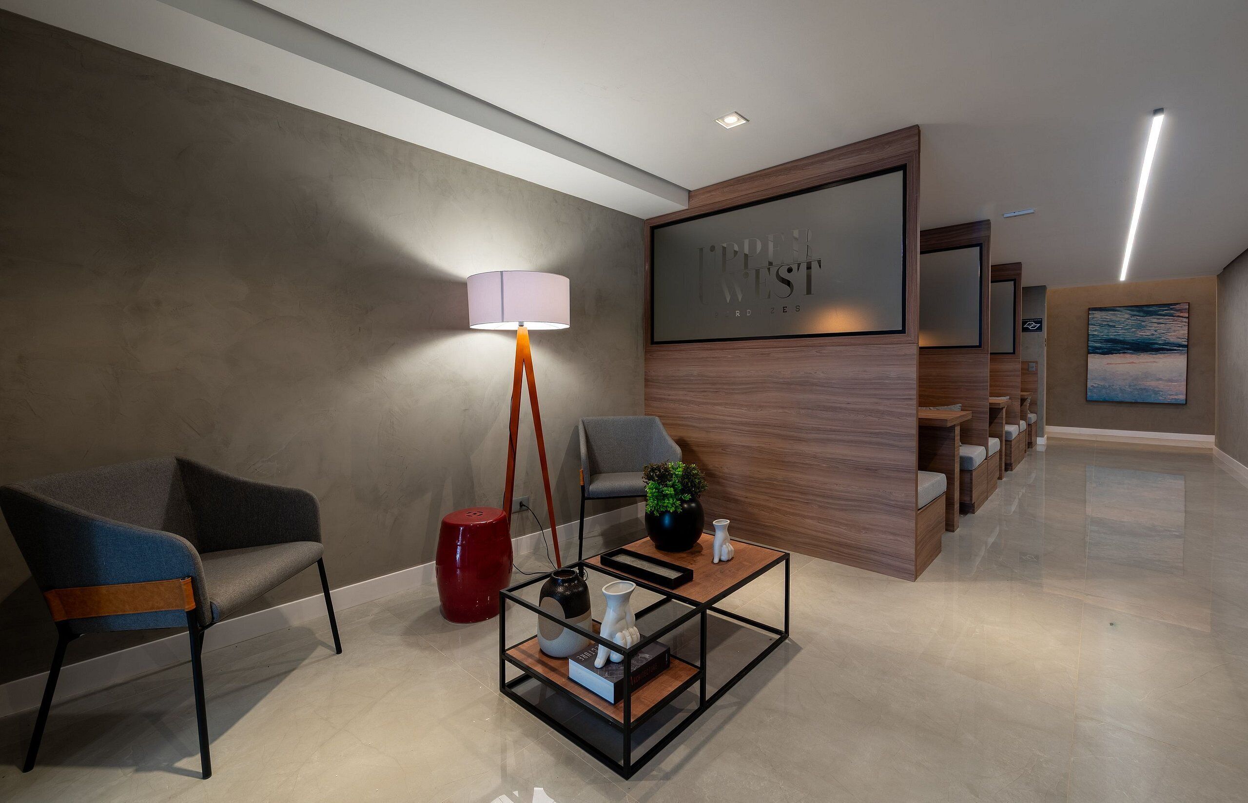 Un área de espera moderna con un sofá, una mesa de centro, una lámpara y un mostrador de recepción.