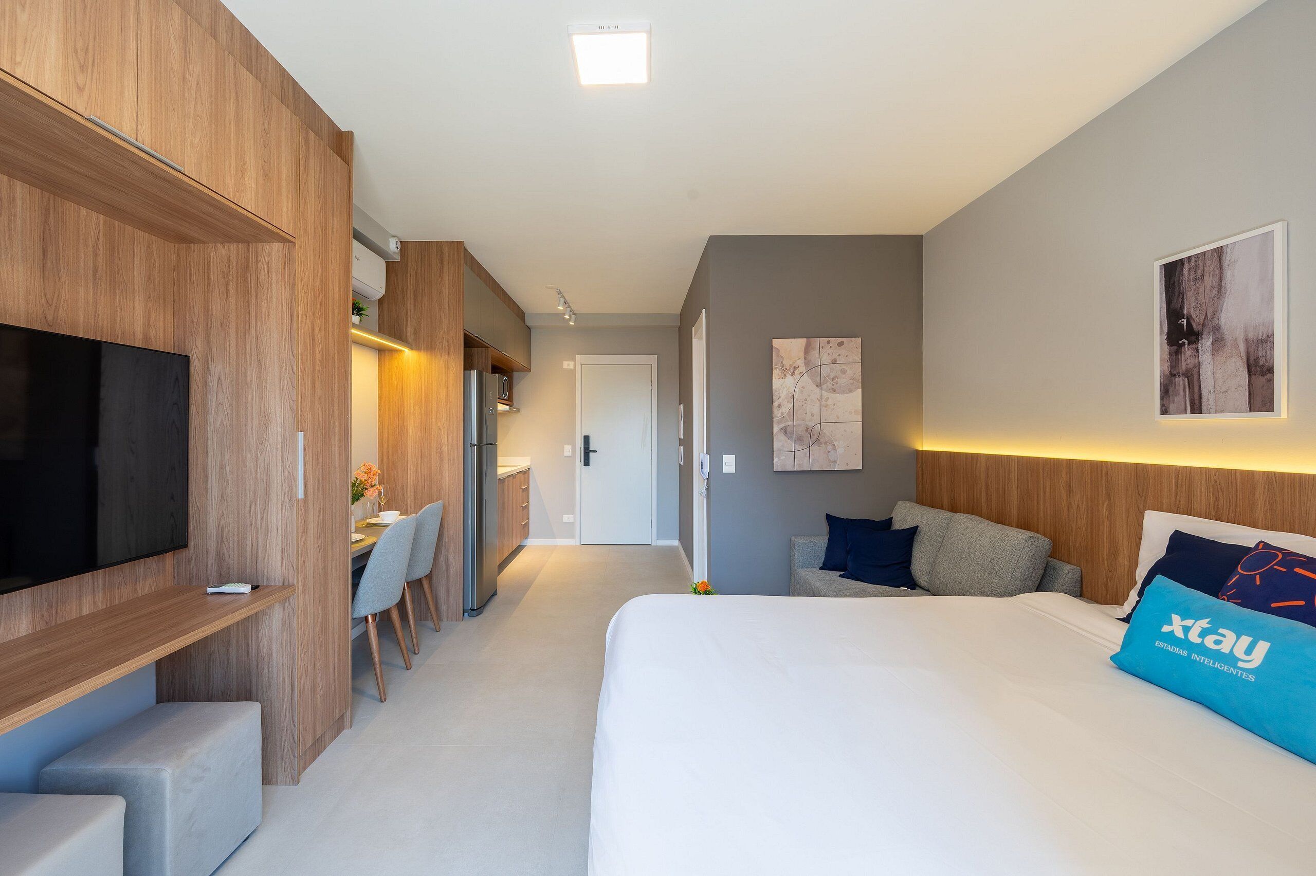 Una habitación de hotel moderna con una cama grande, televisión, escritorio y zona de comedor.
