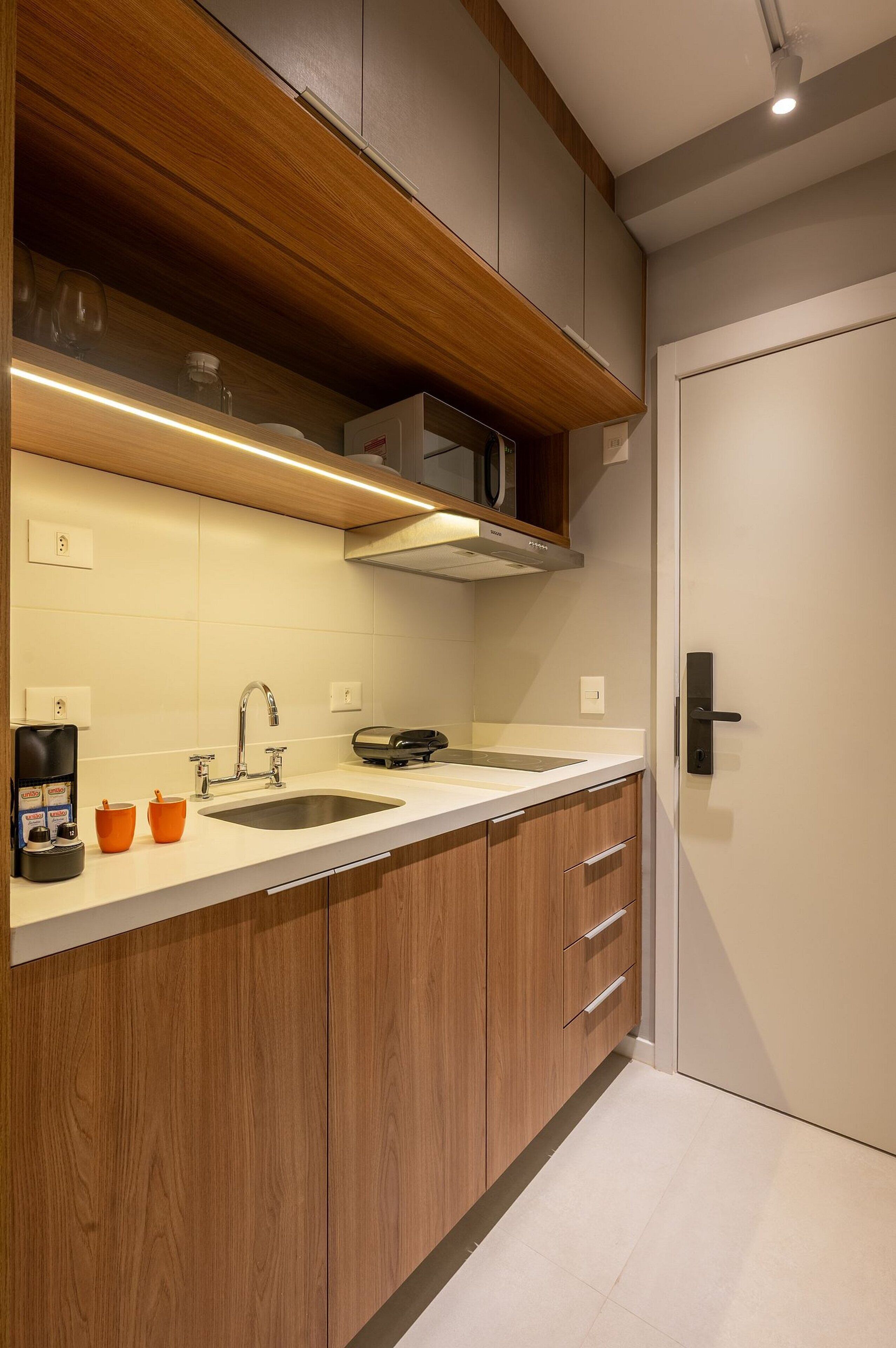 Une cuisine moderne avec des meubles en bois, un évier en acier inoxydable et un four à micro-ondes encastré.