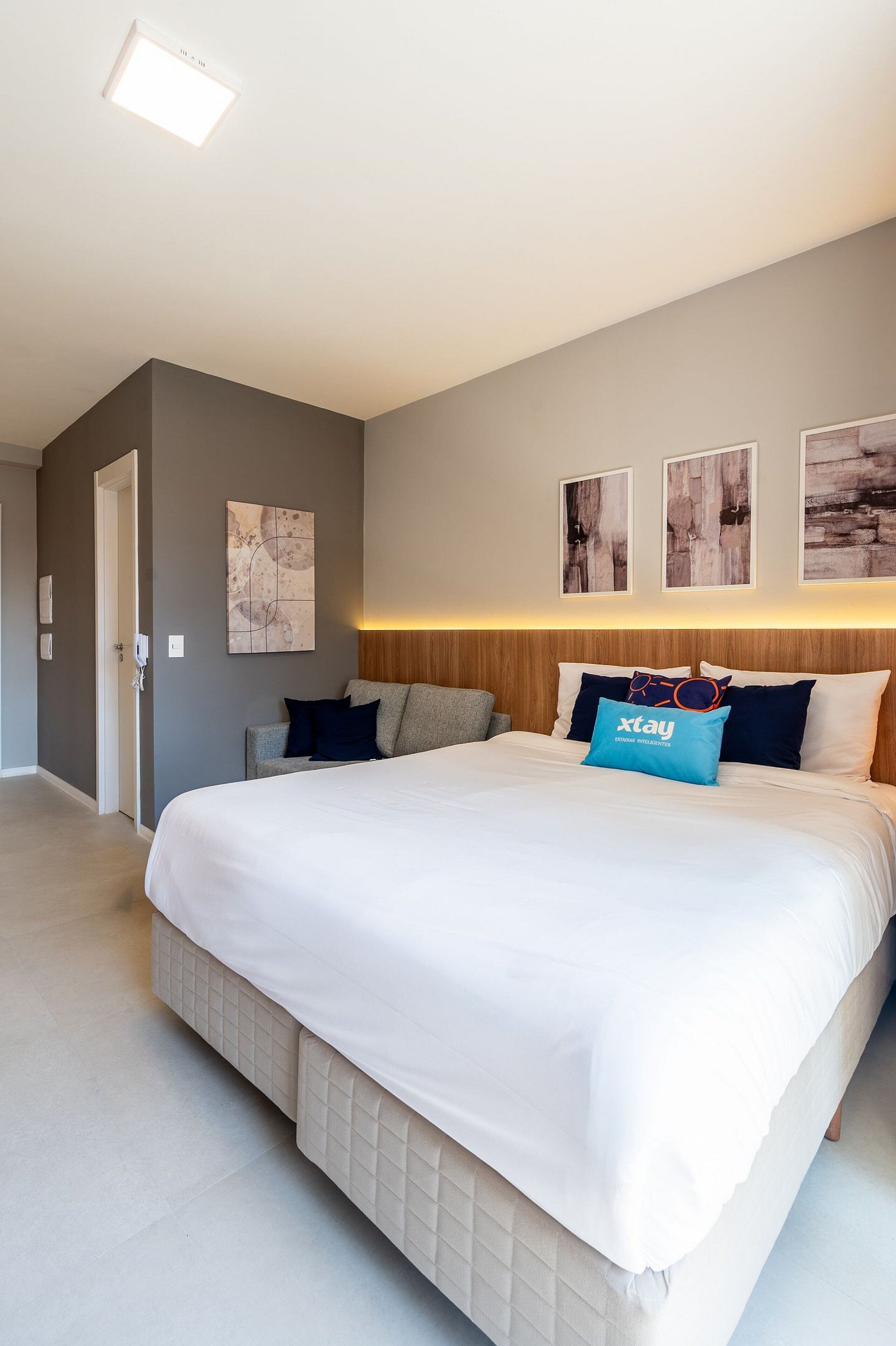 Et moderne hotelværelse med en stor seng, et træhovedgærde og et lille siddeområde.