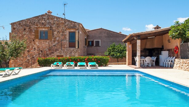 Edifici de pedra amb una piscina, seients a l'aire lliure i un bou salvavides.