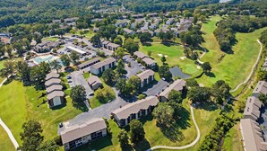 An aerial view of a residential area with multiple apartment buildings, a golf course, and a dam in the background. - Serene on Seventeen - For 4 (Branson)