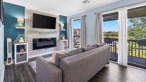 A modern living room with a flat-screen TV, grey sofa, and a fireplace. - Serene on Seventeen - For 4 (Branson)