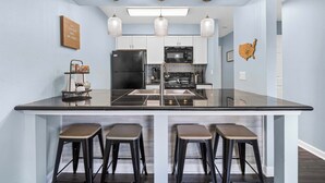 A modern kitchen with a central island, bar stools, and a microwave. - Serene on Seventeen - For 4 (Branson)