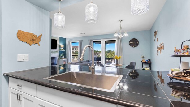 A modern kitchen with a large island, stainless steel sink, and pendant lighting. - Serene on Seventeen - For 4 (Branson)