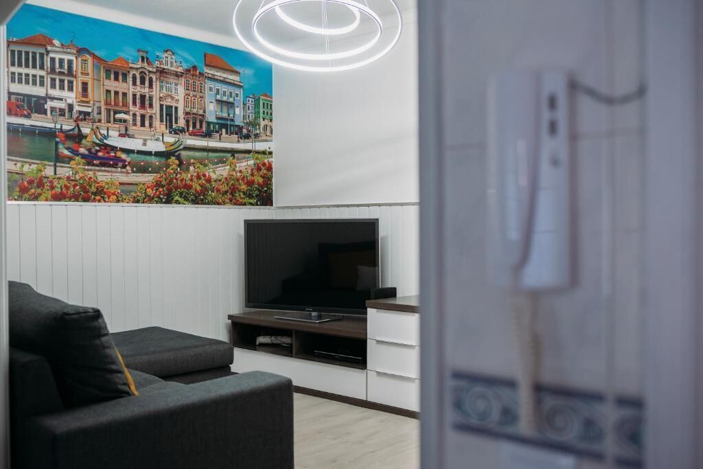 Ein modernes Wohnzimmer mit Flachbildfernseher, grauem Sofa und einem Gemälde einer Kanalansicht.