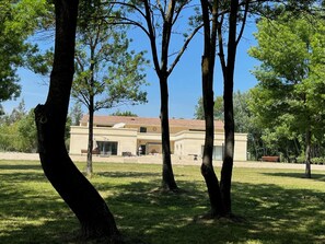 Un bâtiment avec un toit en tuiles, entouré d’arbres et d’une pelouse verdoyante.