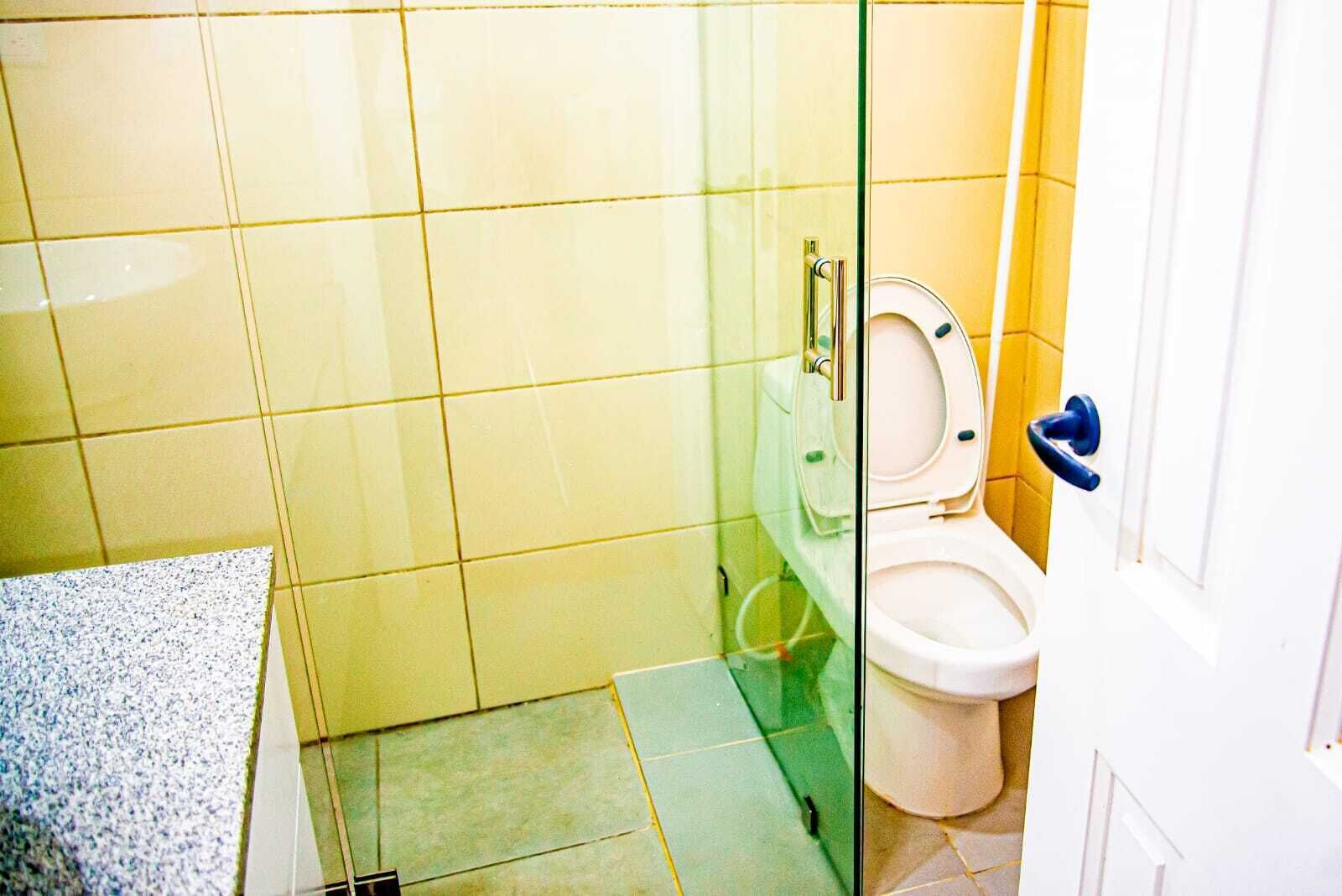 A bathroom with a glass partition, a toilet, and a sink.