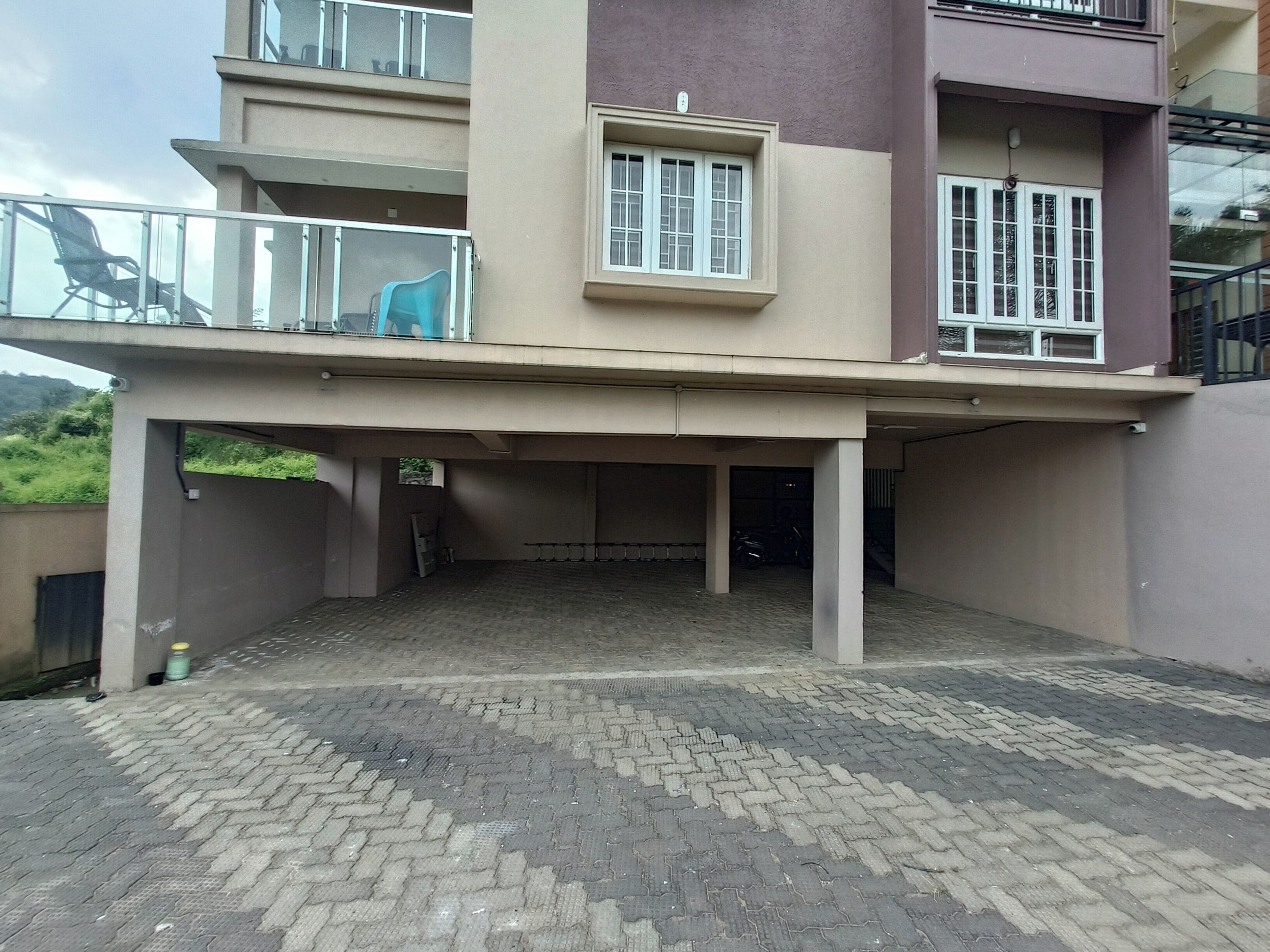 Een gebouw met twee verdiepingen, een overdekte parkeerplaats en een balkon.