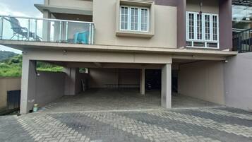 A two-story building with a covered parking area and a balcony.