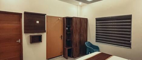 A bedroom with a bed, wardrobe, and a window with blinds.