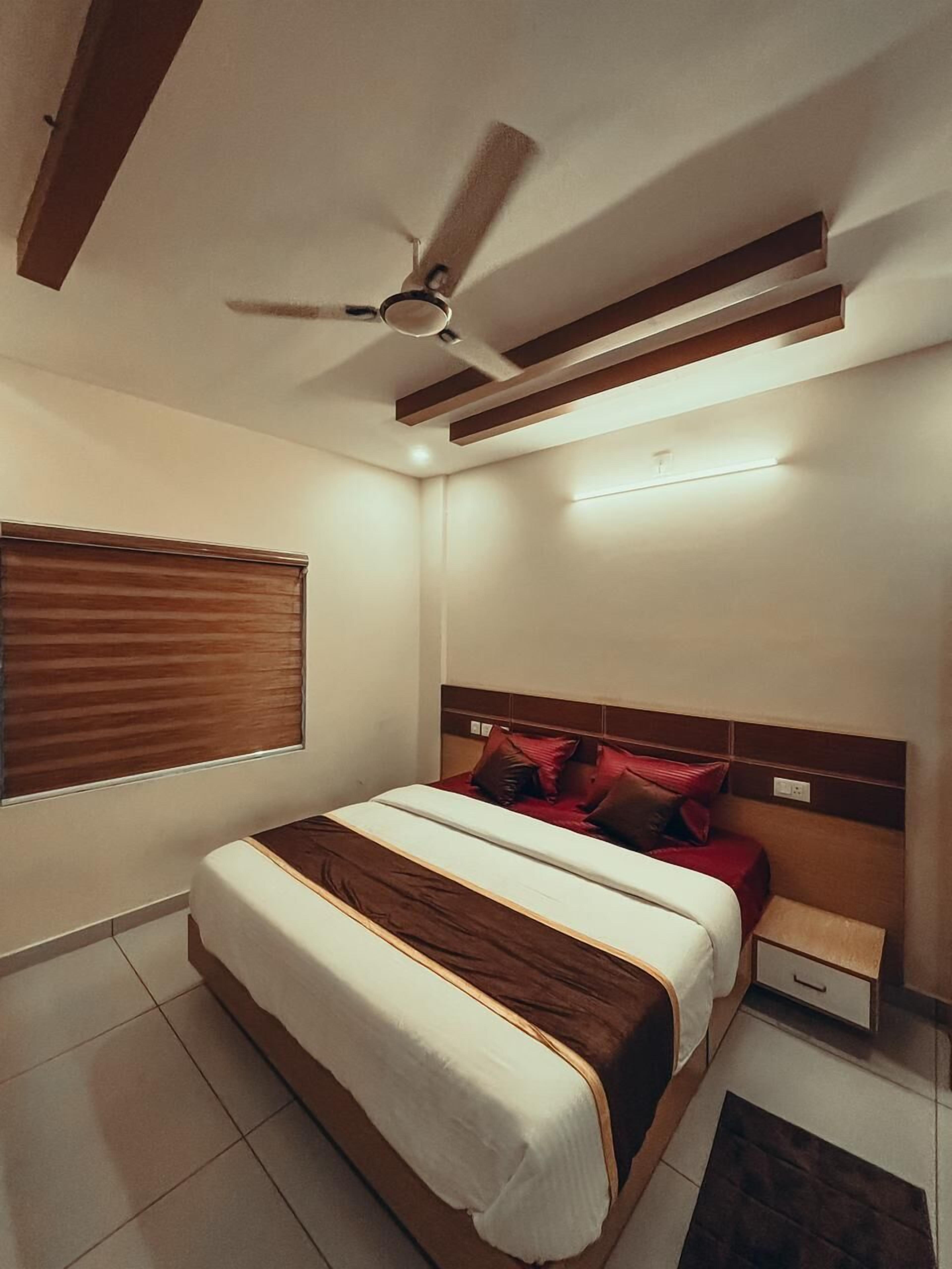 A bedroom with a bed, a nightstand, a ceiling fan, and a window with blinds.