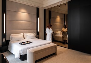 Una habitación de hotel moderna con una cama grande, mesitas de noche y un espejo.