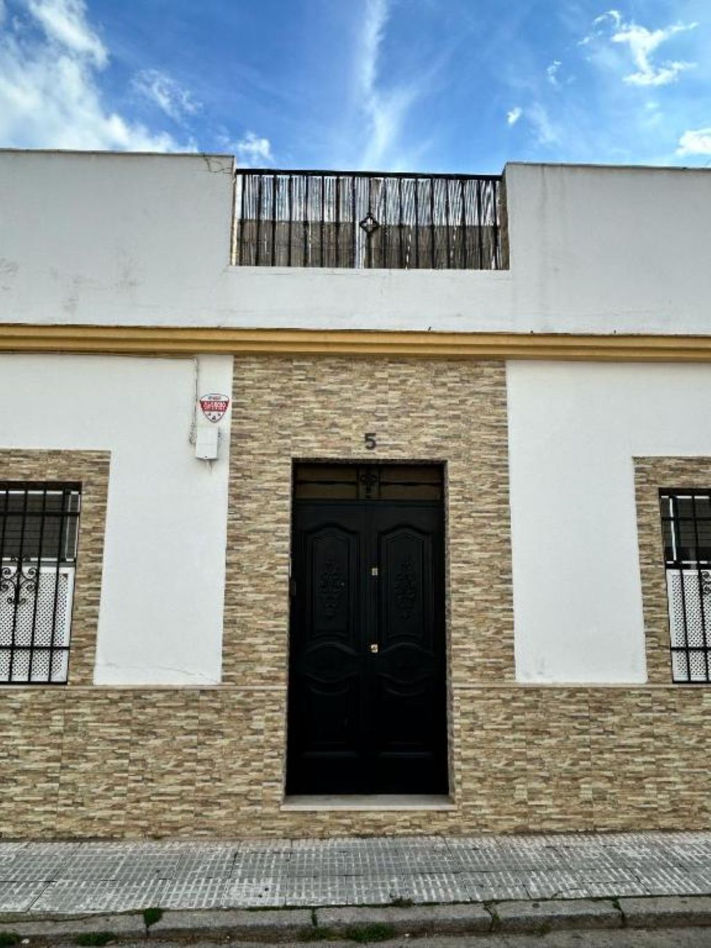 A building with a black door, number 5, and two windows with metal bars.