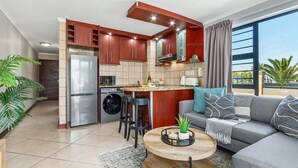 Eine moderne Küche mit Backofen, Kühlschrank und einer Essecke mit einem runden Holztisch.