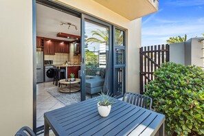 A modern kitchen with dark cabinetry and a dining area with a table and chairs. - Sandy Bay C5 (Cape Town)