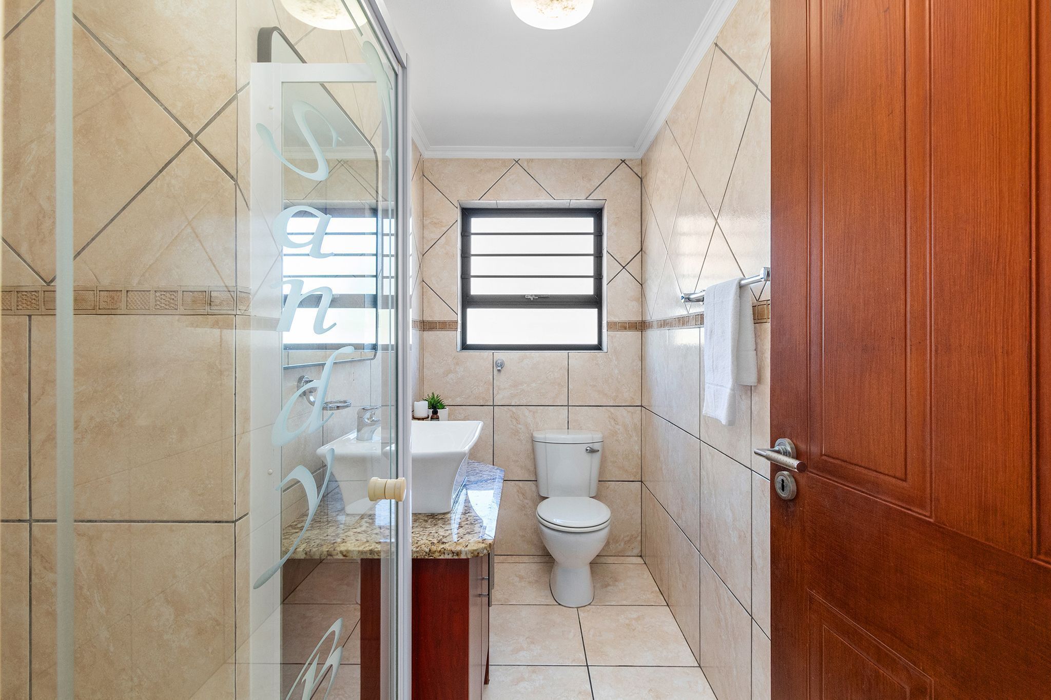 A bathroom with a glass shower enclosure, a toilet, and a sink.