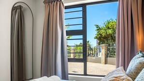Ein Hotelzimmer mit Bett, Fenster mit Vorhängen und Blick nach draußen.