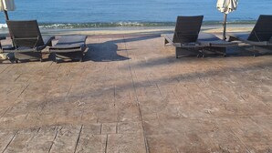 En strandbar med fletningslounge stole og en hvid parasol med udsigt over havet.