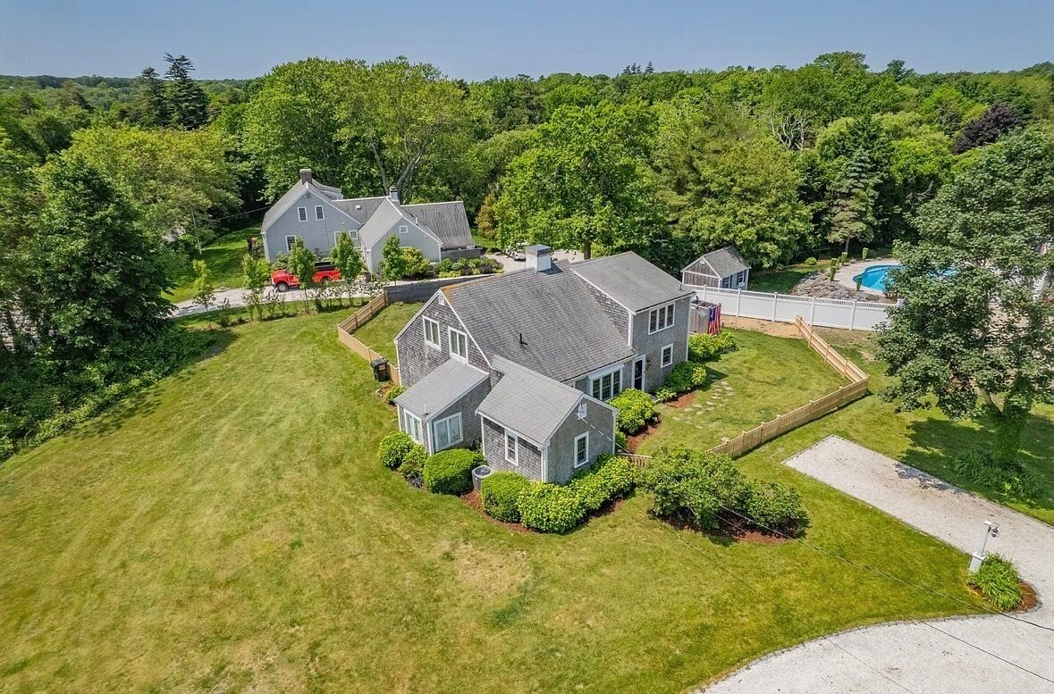 A large house with a well-maintained lawn, a swimming pool, and a fenced yard.