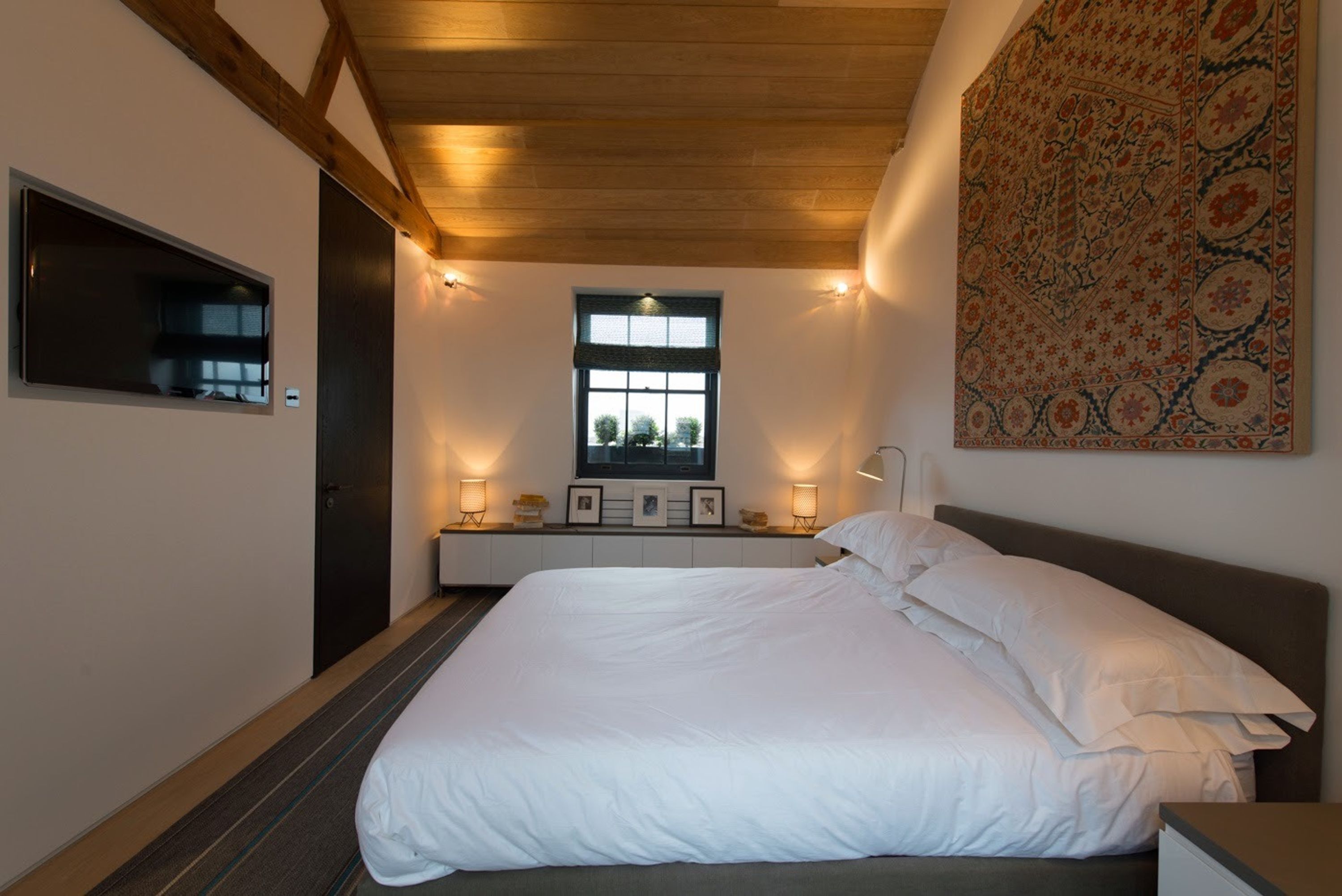 Een slaapkamer met een groot bed, een raam met uitzicht en een wandtapijt aan de muur.