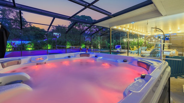 A hot tub with a glass enclosure, surrounded by lounge chairs and a pool area. - New listing discount! 5BR luxe oasis: Pickleball+bowling+golf+game room & more! (Bradenton)