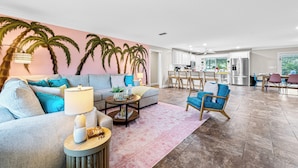 A spacious living room with a sofa, coffee table, and a dining area with chairs and a table. - New listing discount! 5BR luxe oasis: Pickleball+bowling+golf+game room & more! (Bradenton)