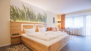 Una habitación de hotel moderna con una cama de madera, un escritorio y un ventanal con cortinas.