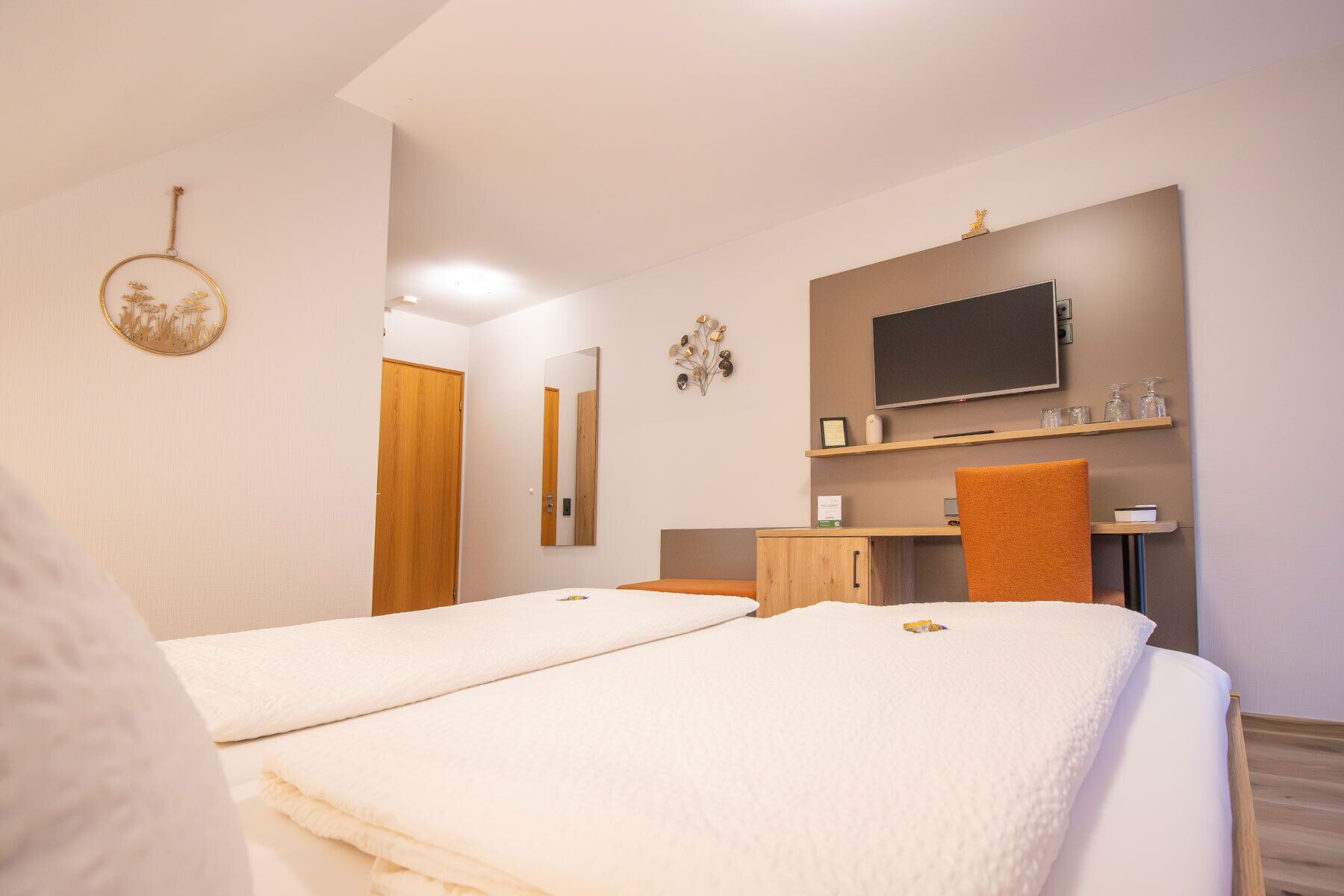 Habitació d'hotel amb dos llits, una televisió, un petit armari i un mirall.