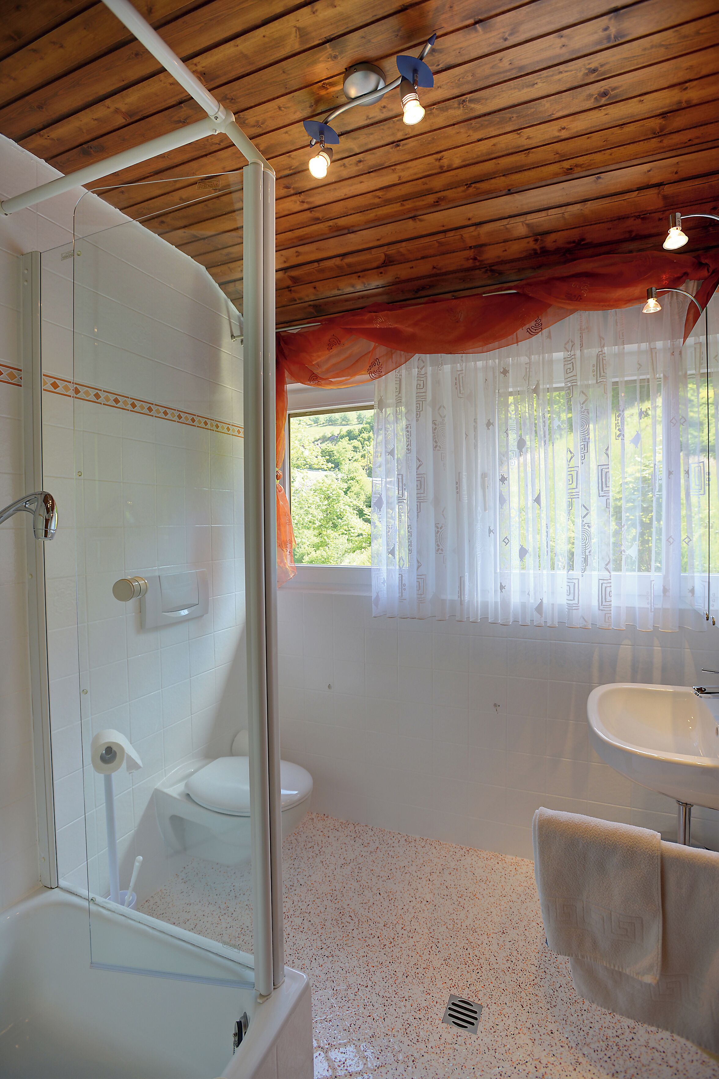 Un baño con ducha, inodoro, lavamanos y toallero.