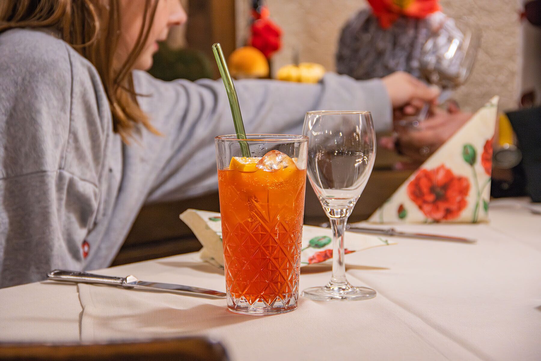 Une table avec un verre de boisson à l’orange, un verre à vin, un couteau et une serviette.