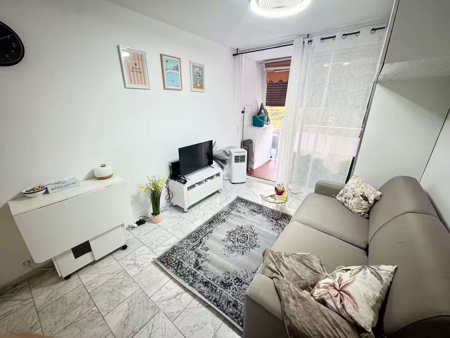 Ein modernes Wohnzimmer mit einer Couch, Fernseher und einer kleinen Essecke.