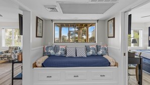 A bedroom with a built-in bench bed, a window with a view, and a desk with a chair. - Port O' Call D102 - Walkout to Beach/Ocean! (Isle of Palms)
