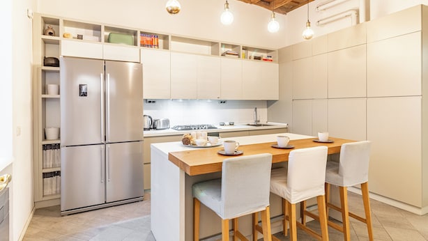 A modern kitchen with a built-in island, stainless steel appliances, and pendant lighting. - Suite Manzoni by Houset (Monza)