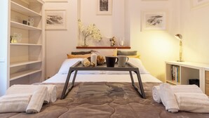 A neatly arranged bedroom with a bed, bedside tables, a shelf with books, and framed pictures on the wall. - Suite Manzoni by Houset (Monza)