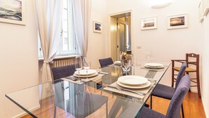 A modern dining area with a glass table, chairs, and a view of the cityscape through the window. - Suite Manzoni by Houset (Monza)