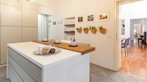 A modern kitchen with a central island, wooden countertops, and hanging planters. - Suite Manzoni by Houset (Monza)