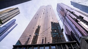 A high-rise building with a modern architectural design, featuring a prominent glass facade and a series of vertical lines. - Home in the Sky 2BR,2BA with City Views,Pool & Gym (Melbourne)