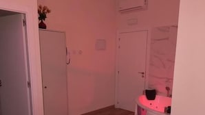 Quarto de hotel com uma cama, uma penteadeira com espelho e uma porta.