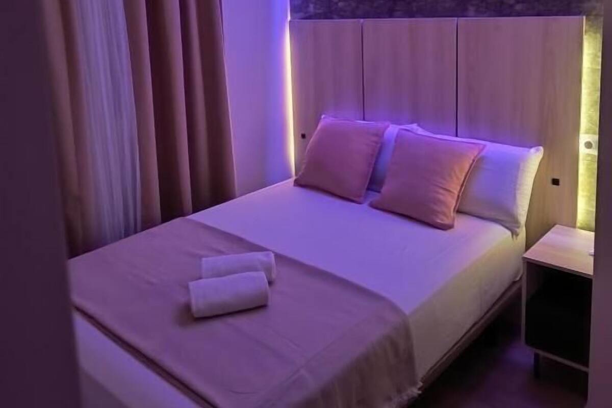 A modern bedroom with a bed, pillows, and a nightstand.