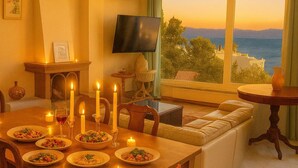A dining area with a table set for a meal, candles, and a view of the sea. - Caecilia Lawrence Bio Sea Villa - Sleeps 12 (Chalcis)