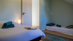 Une chambre à coucher avec un lit, une table de chevet, un petit canapé et une porte.